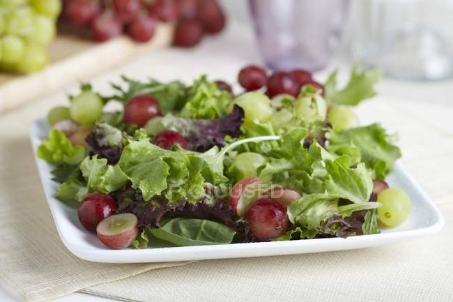 Vista close-up de salada verde mista orgânica com uvas vermelhas e verdes — Fotografia de Stock