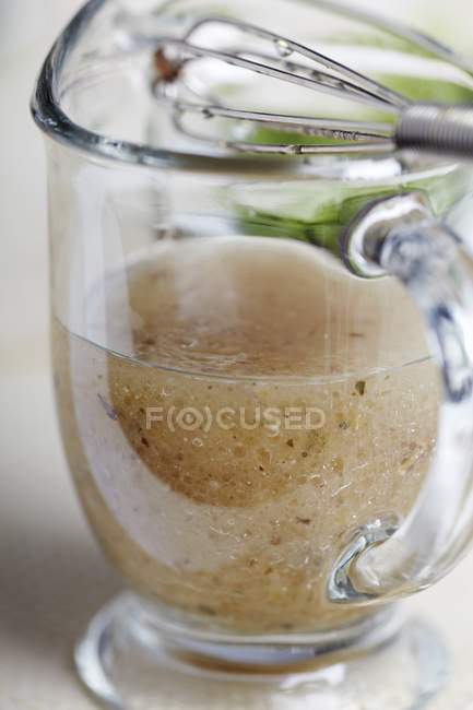 Vista da vicino dell'insalata italiana Vinaigrette fatta in casa condimento in una brocca di vetro con una frusta — Foto stock