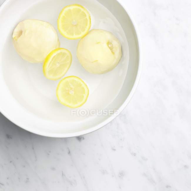 Свежие чищенные айвы с ломтиками лимона — стоковое фото