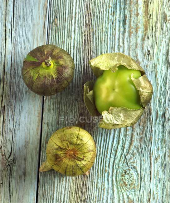 Three Tomatillos on green Distressed Wood — Stock Photo