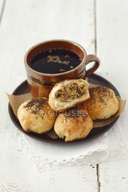 Bread rolls with sauerkraut and mushrooms in small pot over plate over wooden surface — Stock Photo