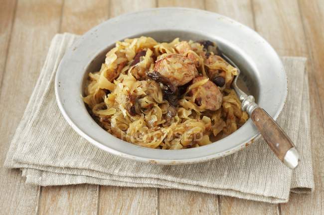 Bigos sauerkraut with sausage and bacon on white plate over towel — Stock Photo