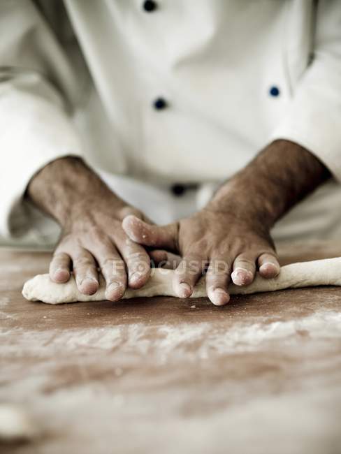 Chef déroulant la pâte gnocchi sur une surface de travail farinée — Photo de stock