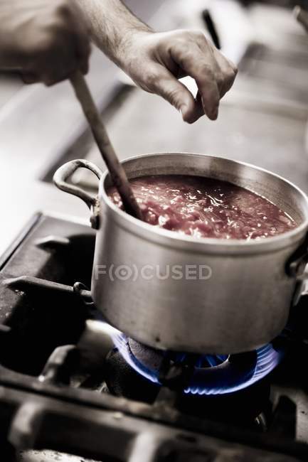 Um molho de tomate tempero cozinheiro com sal na panela no fogão — Fotografia de Stock