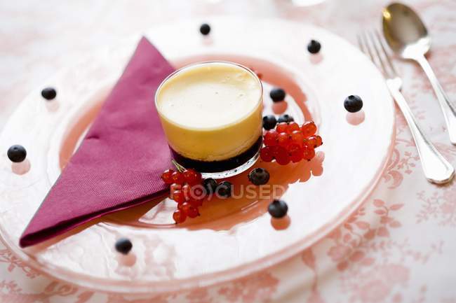 Closeup view of Creme caramel in glass with blueberries and red currants on plate — Stock Photo
