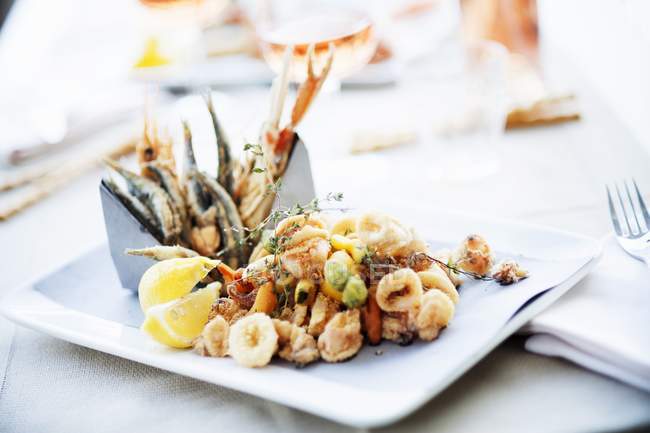 Closeup view of Fritto misto with lemon wedges on platter — Stock Photo