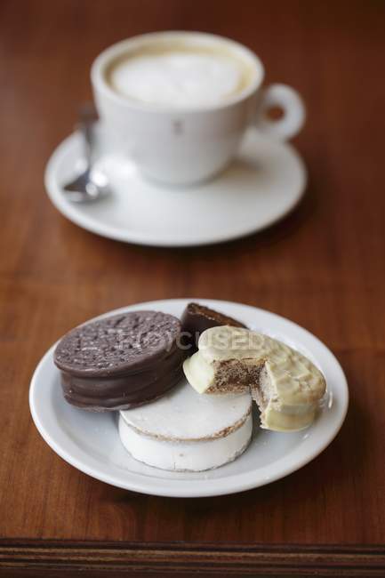 Closeup view of chocolate cookies with cup of coffee on plates — Stock Photo