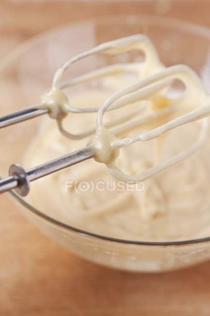 Vista close-up de mistura de bolo em uma tigela de vidro e nas batedeiras do misturador — Fotografia de Stock