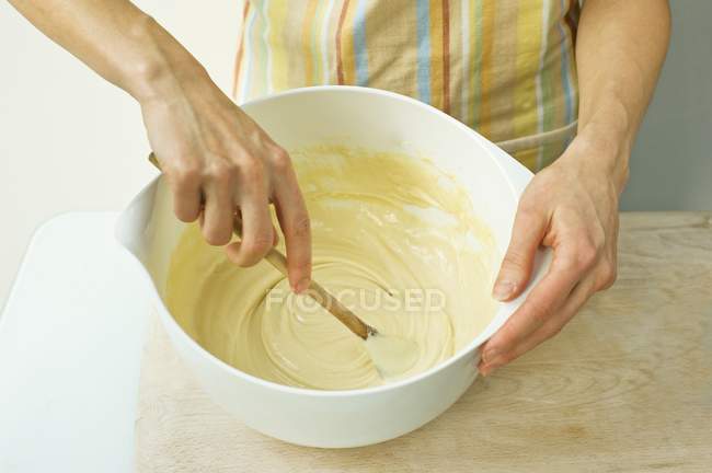 Femme mélangeant la pâte avec une cuillère en bois dans un bol — Photo de stock
