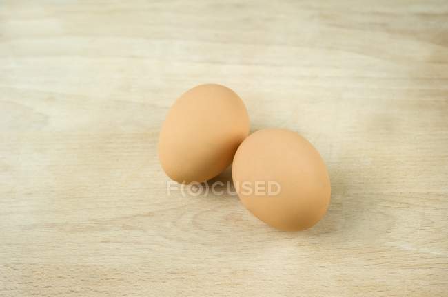 Huevos frescos sobre una superficie de madera - foto de stock