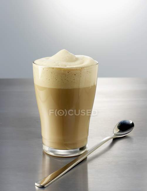 Glass of latte macchiato with spoon — Stock Photo