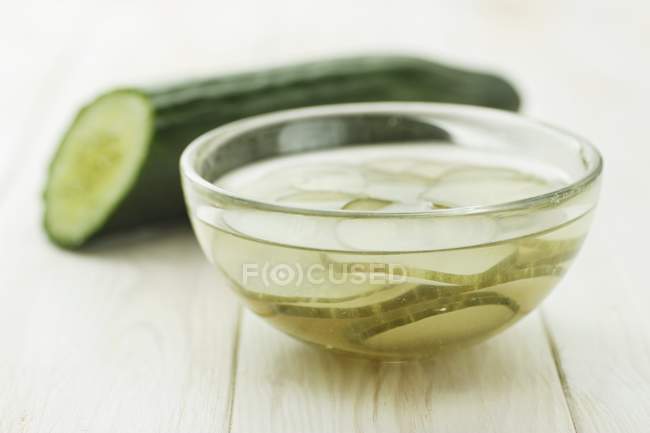 Half of fresh cucumber and dish of pickled — Stock Photo