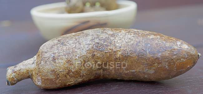 Cassava cruda sin pelar que pone en la superficie marrón claro - foto de stock