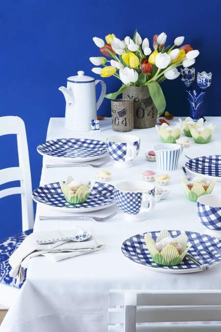 Vue surélevée d'une table posée avec des cupcakes et des fleurs — Photo de stock
