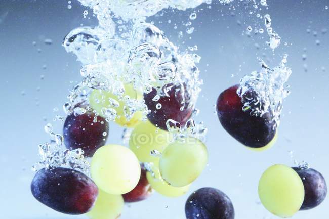 Grapes falling into water — Stock Photo