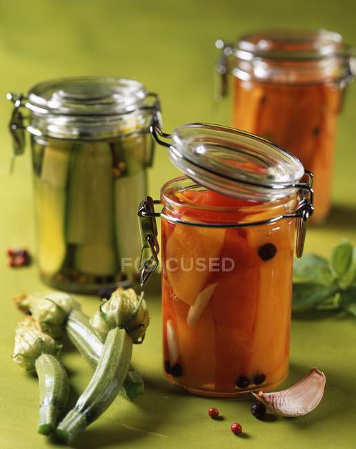 Légumes conservés dans l'huile dans des pots sur une surface verte — Photo de stock