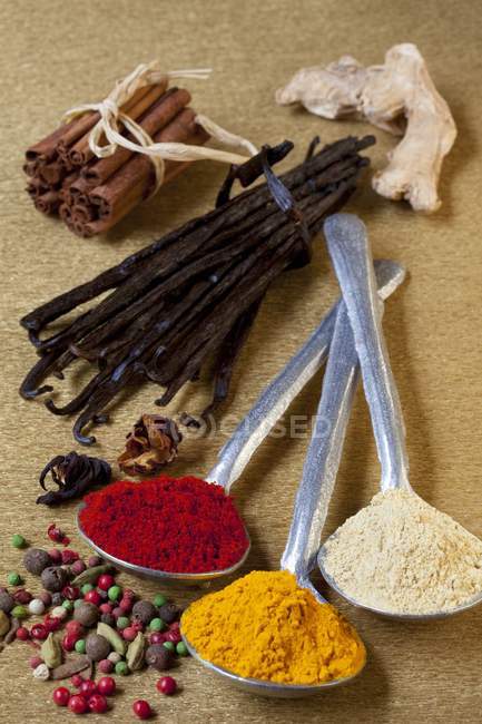Closeup view of assorted powdered and whole spices with spoons — Stock Photo