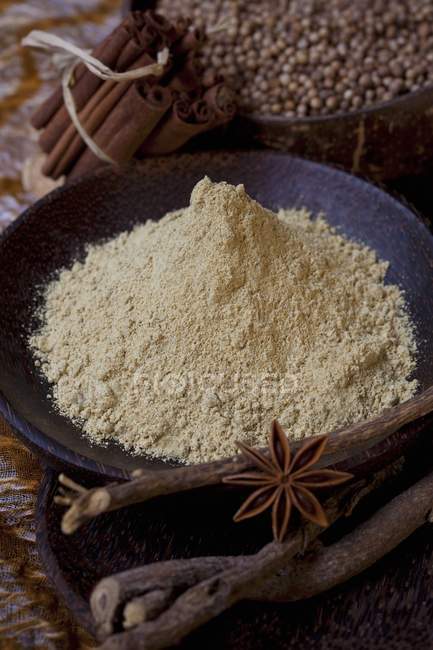 Liquorice root powder in a bowl, surrounded by spices — Stock Photo