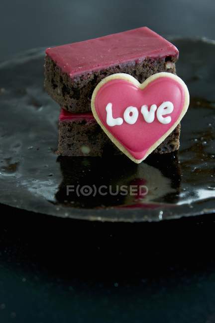 Serving of brownies decorated with red icing — Stock Photo