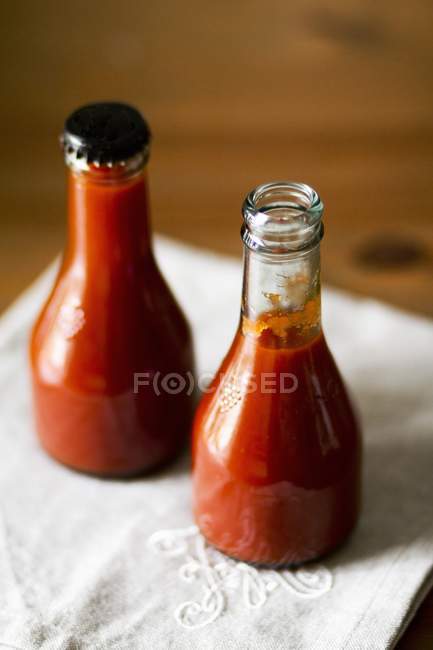 Bottles of home-made ketchup over towel — Stock Photo