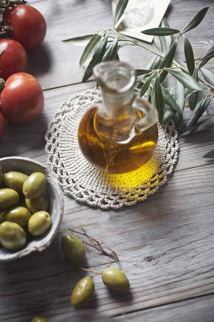 Aceite de oliva en una jarra de vidrio sobre una superficie de madera - foto de stock