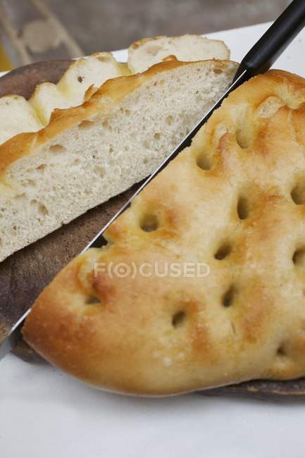 Closeup view of a cut Focaccia with a knife — Stock Photo