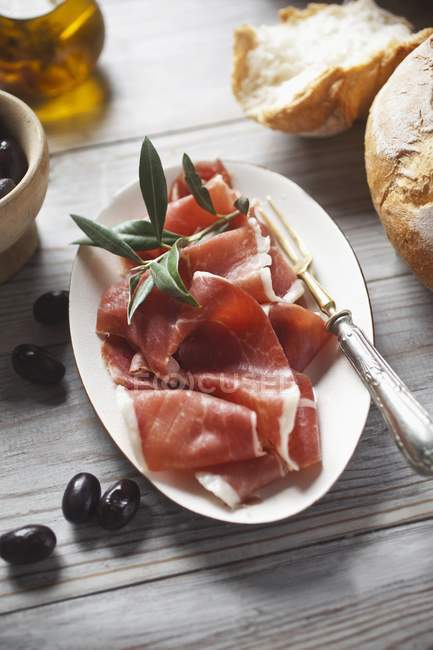Serrano ham slices with bread and olives — Stock Photo