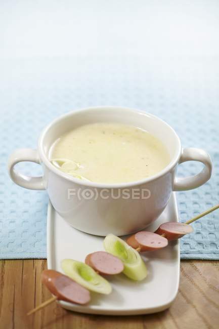 Creamy soup with sausage and leek skewer — Stock Photo