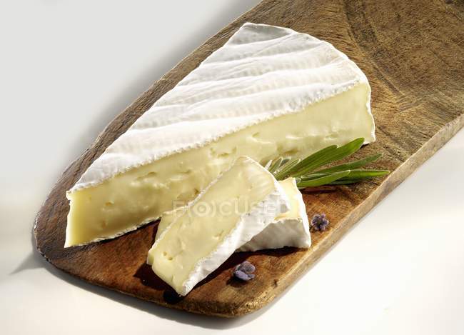 Brie with slices on chopping board — Stock Photo