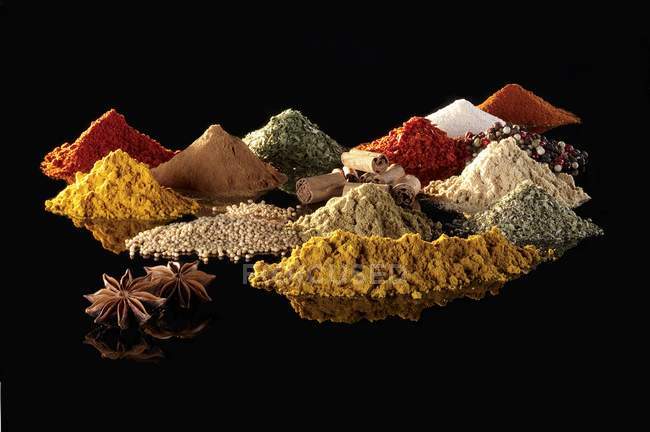 Closeup view of various spices heaps on black reflective surface — Stock Photo