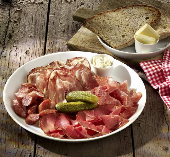 Sausage and ham platter with pickled gherkins — Stock Photo