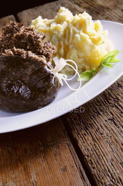 Aggeo con purè di patate su piatto bianco su superficie di legno — Foto stock