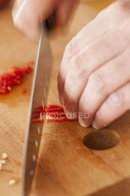 Mãos humanas cortando pimentas vermelhas — Fotografia de Stock