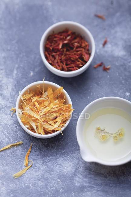 Top view of dried petals and tincture in bowls — Stock Photo