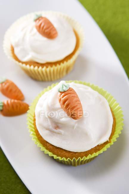 Cupcakes com cobertura e pequenas cenouras doces — Fotografia de Stock