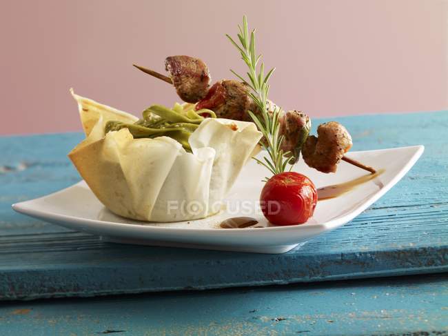 Meat kebabs with green tagliatelle pasta — Stock Photo