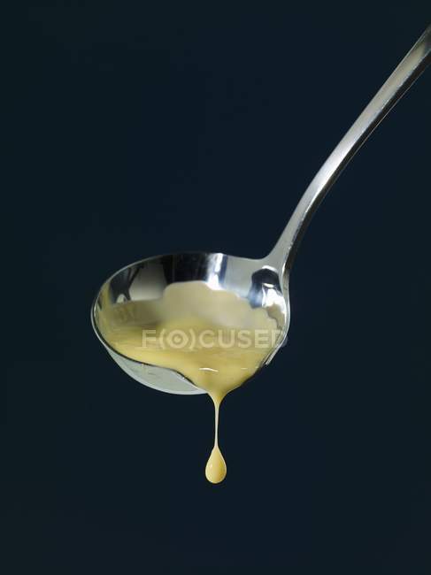 Primo piano vista di salsa alla vaniglia gocciolante dal mestolo — Foto stock
