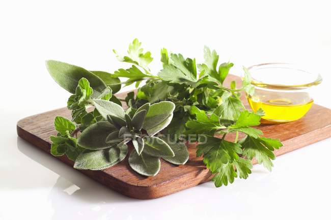 Bodegón con de hierbas frescas y aceite sobre tabla de madera - foto de stock
