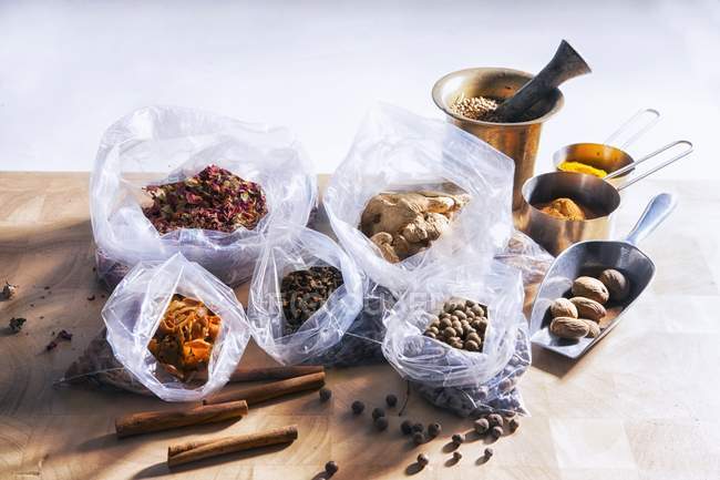 Elevated view of assorted spices with plastic bags and metal dishes — Stock Photo