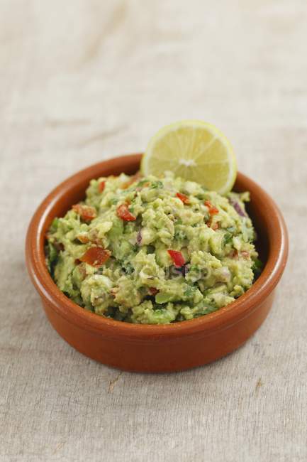 Classic Guacamole in a Glass Bowl and  Fresh Avocados — Stock Photo