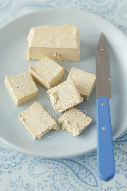 Вид крупным планом нарезанной ванильной халвы с ножом на тарелке — стоковое фото