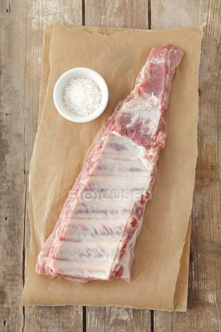Raw Pork ribs on parchment with salt — Stock Photo