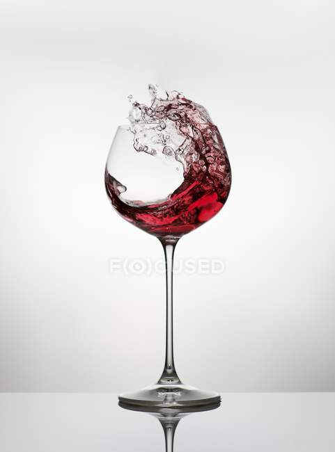 Red wine spattering out of glass — Stock Photo