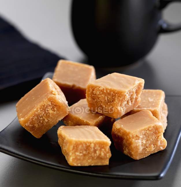 Closeup view of fudge pieces on black square plate — Stock Photo