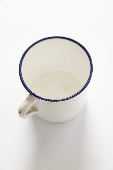 Closeup view of one enamel mug on white surface — Stock Photo