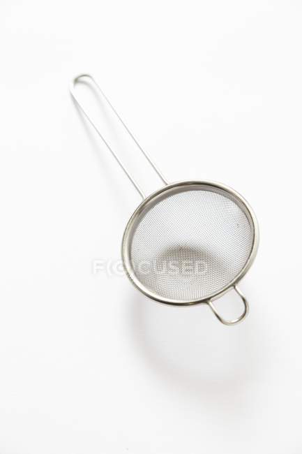 Closeup top view of one small sieve on white surface — Stock Photo
