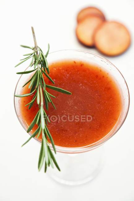 Closeup view of plum drink garnished with a sprig of rosemary — Stock Photo