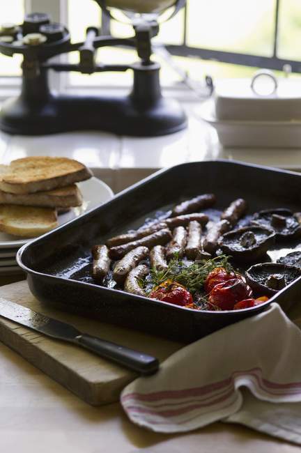 Desayuno inglés con salchichas, champiñones, tomates y tostadas - foto de stock