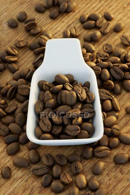 Chicchi di caffè in misurino di porcellana — Foto stock