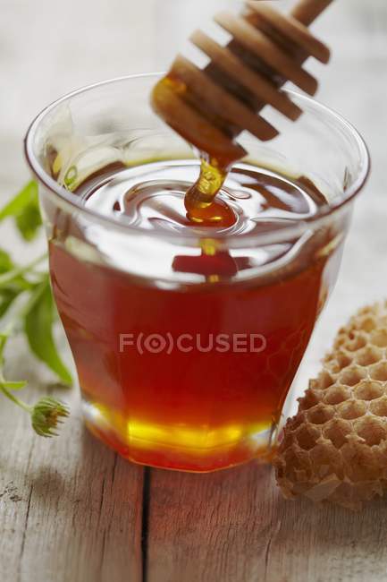 Colher de mel em copo de vidro — Fotografia de Stock